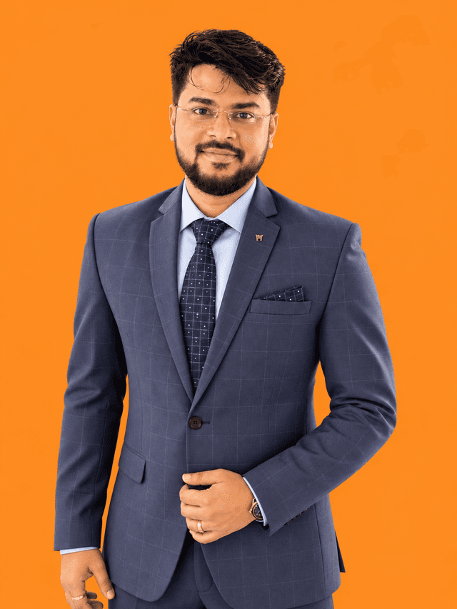 Ayush Das, a studio portrait against a solid orange background, in a navy suit.
